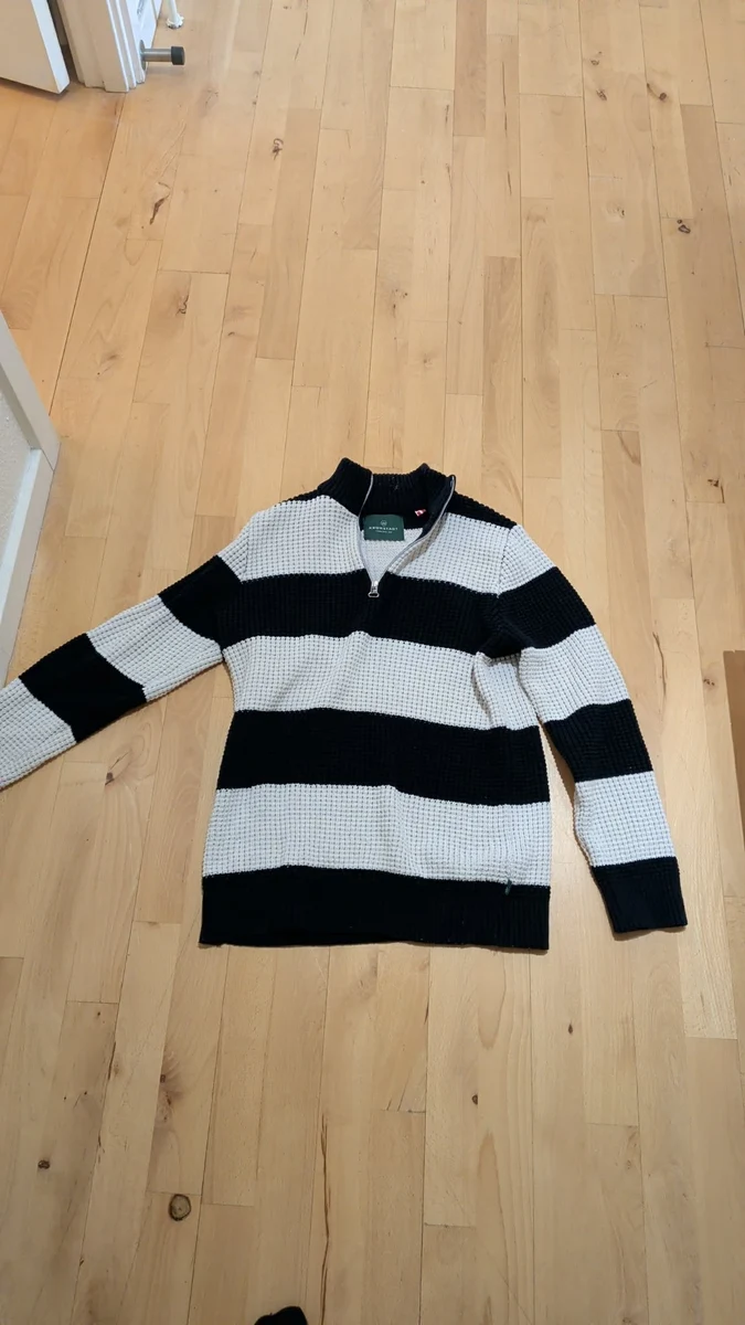 The same striped polo photographed on a wooden floor